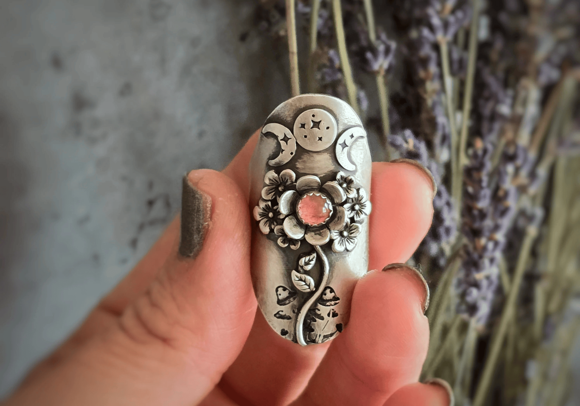 Triple Moon Flower Statement Ring with pink tourmaline held on hand with dried lavender at the background. Size-Inclusive Rings: Handmade Jewelry for Every Finger, Every Body