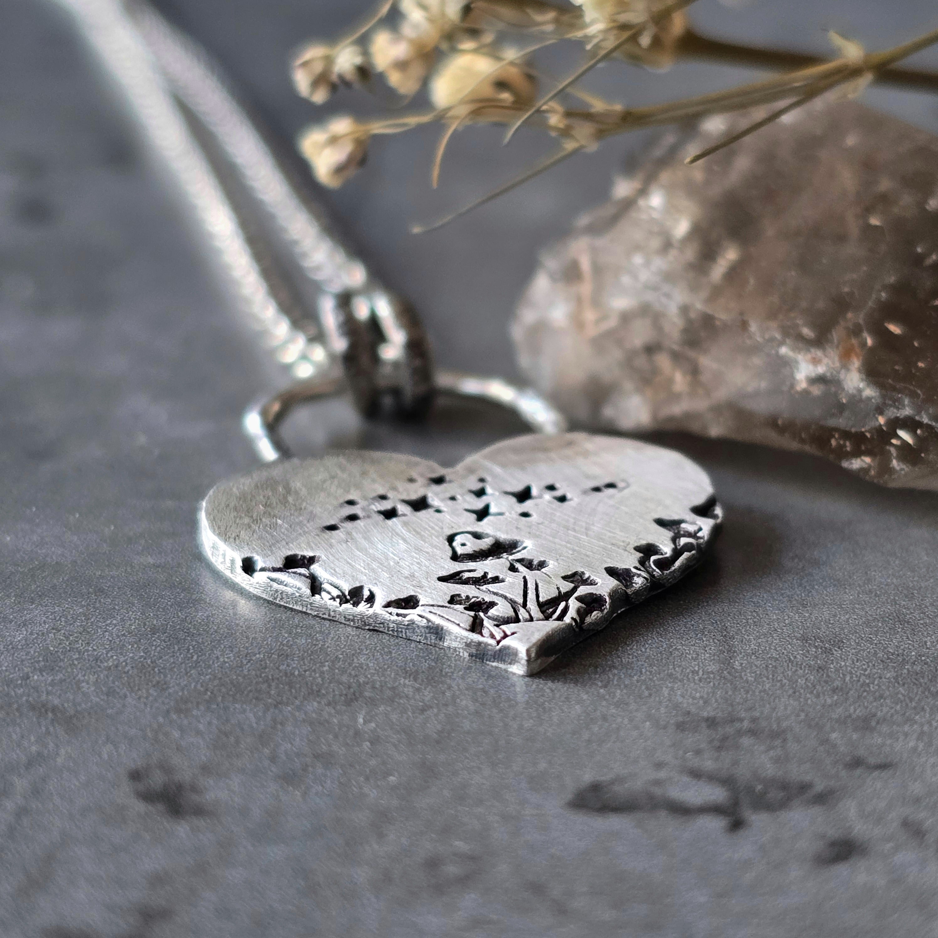 Close-up, flat lay of sterling silver mushroom heart pendant with star and mushroom details