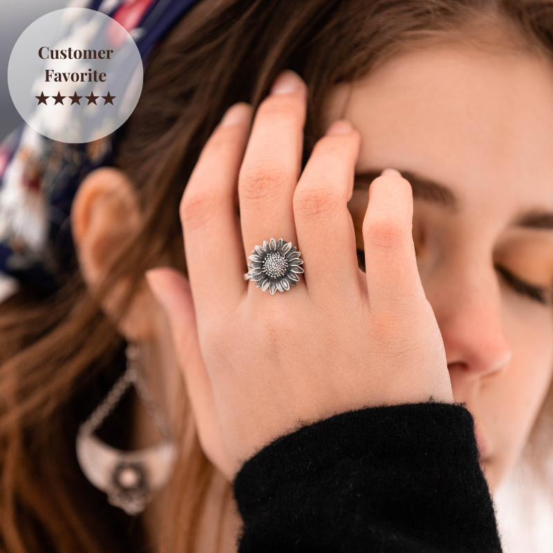 Person wearing a silver sunflower ring with a blurred background