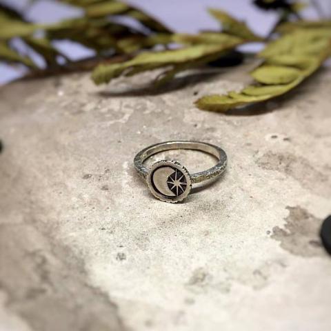 Moon and Star Celestial Ring front view laid on a stone with dried leaves at the background