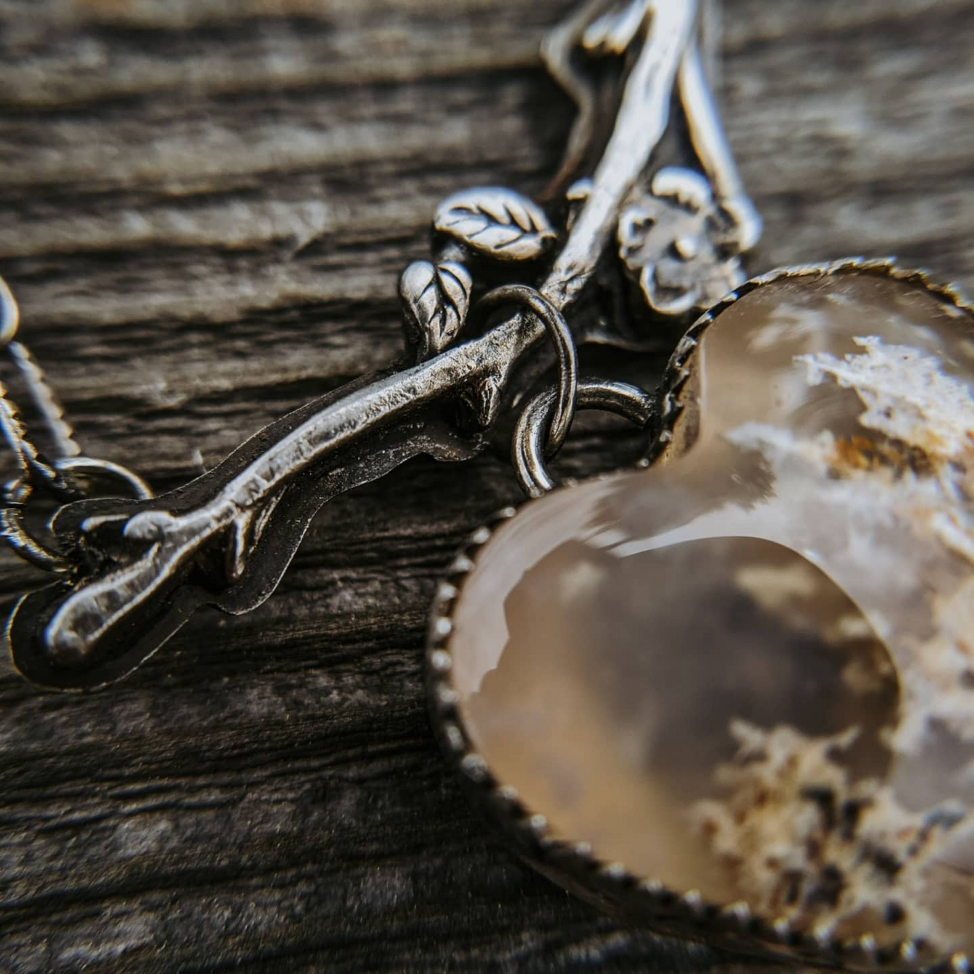 Moss Agate heart stone hanging from a sterling silver branch necklace