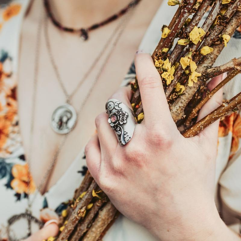 Triple Moon Goddess Ring and Corset Ring on a model who is holding a sunflower