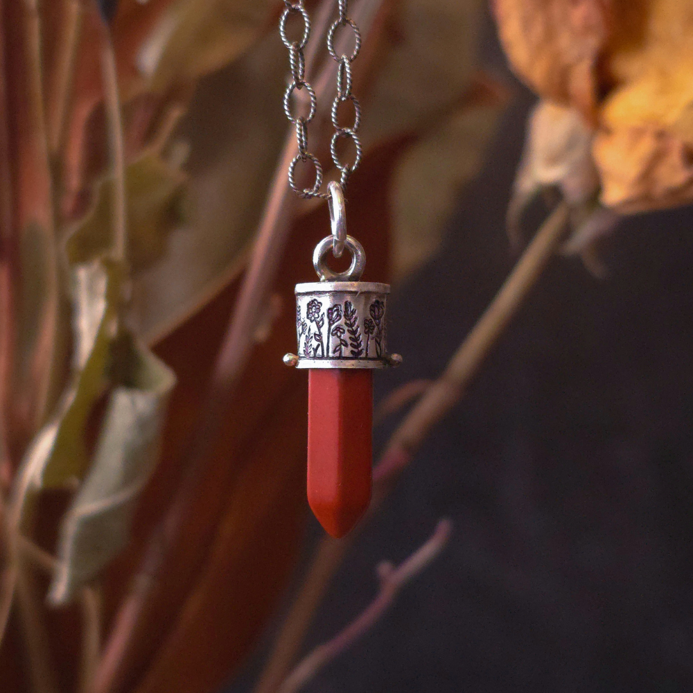 Red jasper charm pendant with silver chain against a natural background
