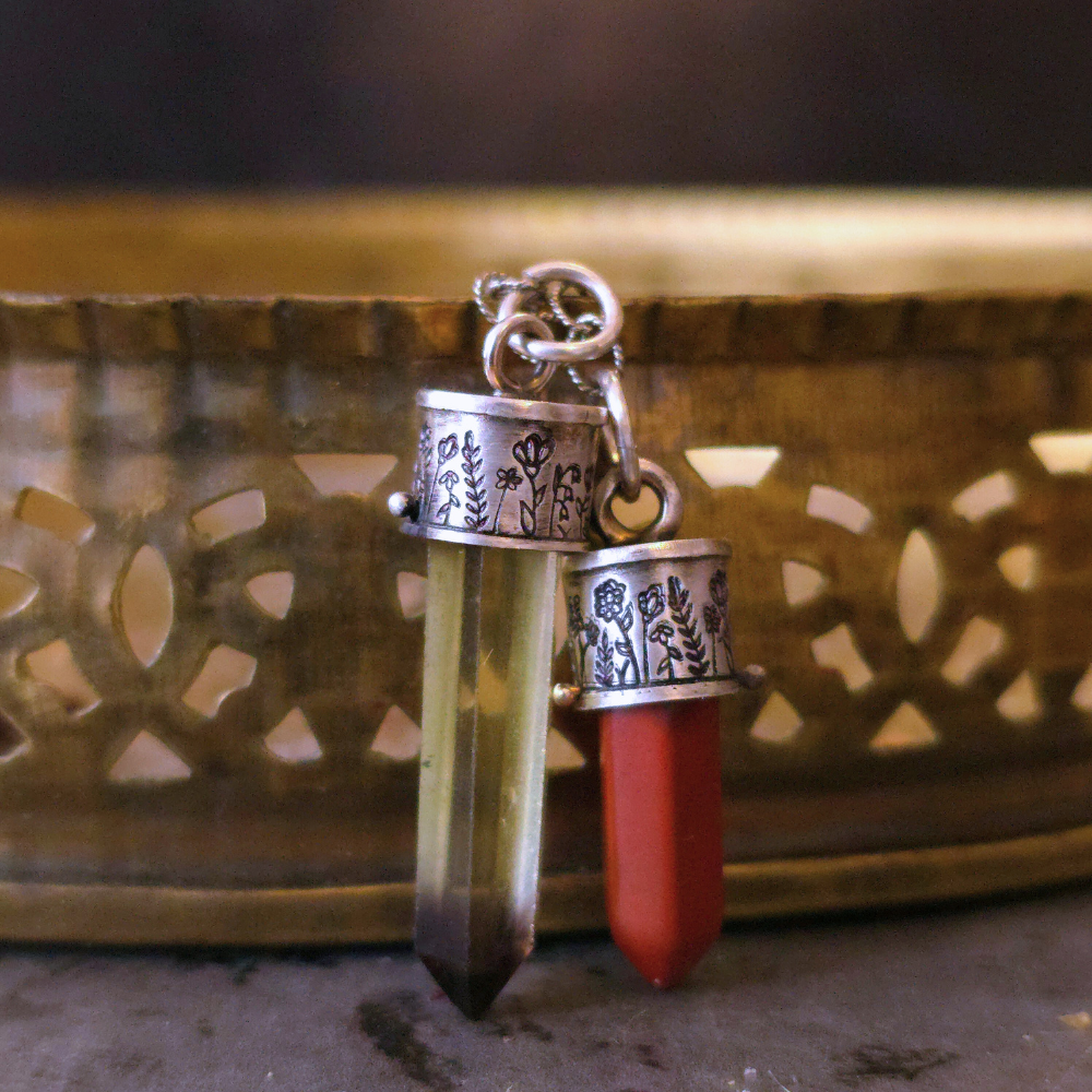 Red Jasper pendant and Smoky Lemon Quarts Wildflowers Lucidity charms together on a textured surface