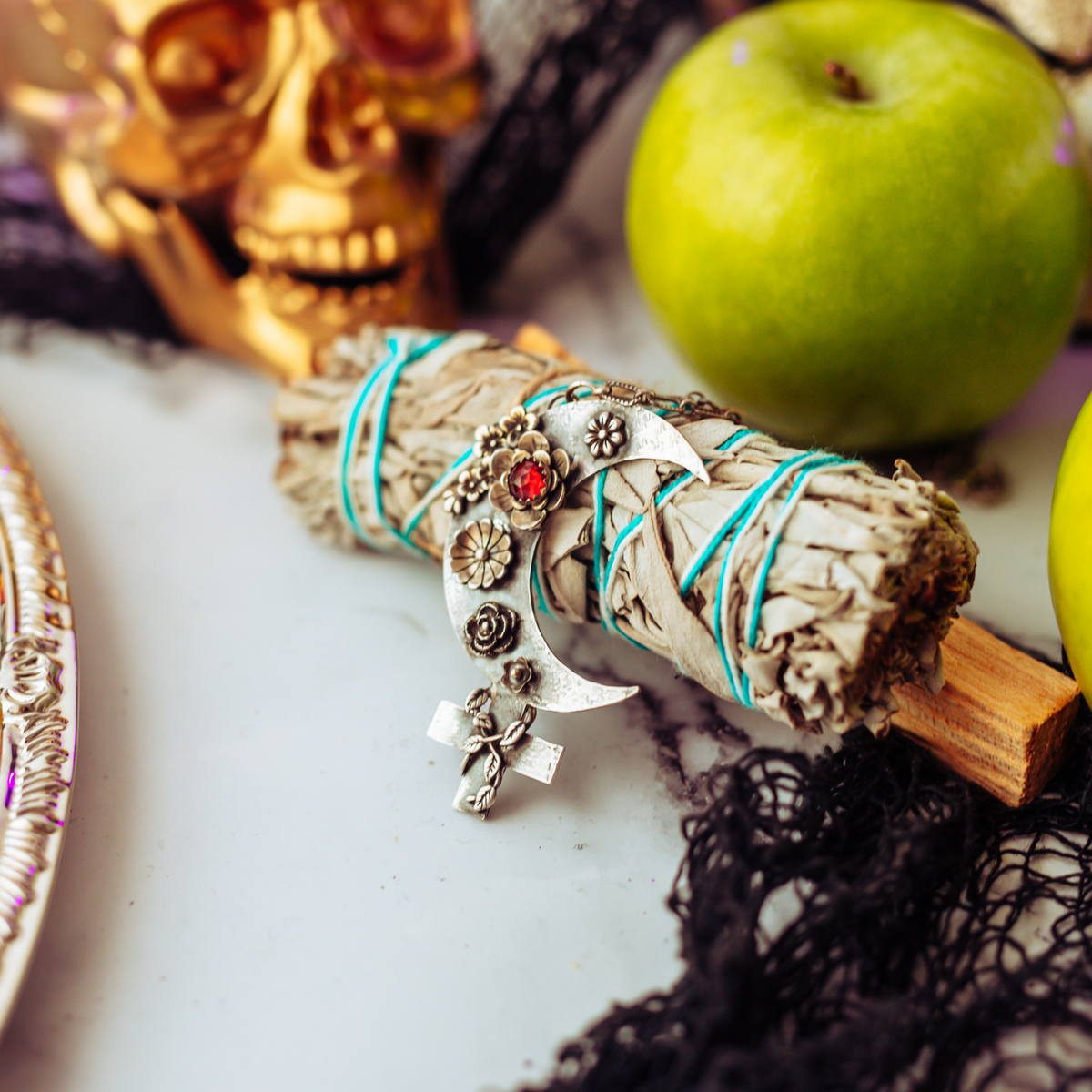 Bonfire Design Black Moon Lilith Necklace with Flowers and Garnet gemstone slaying on a sage and a skull prop at the background