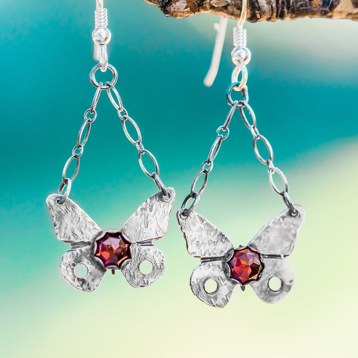 Sterling Silver Butterfly Earrings with Garnet Gemstone hang on a branch
