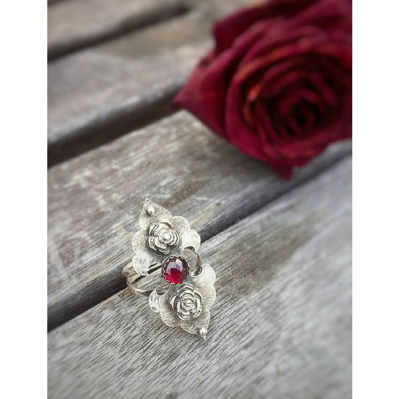 Rosebuds Flower Statement Ring with Garnet slightly side view with a dried red rose in the scene