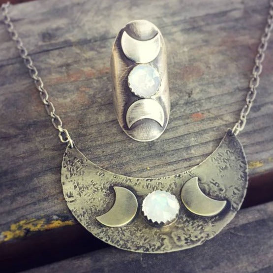Triple Moon Goddess Necklace with Moonstone flat on a table with the triple moon goddess ring matching pair 